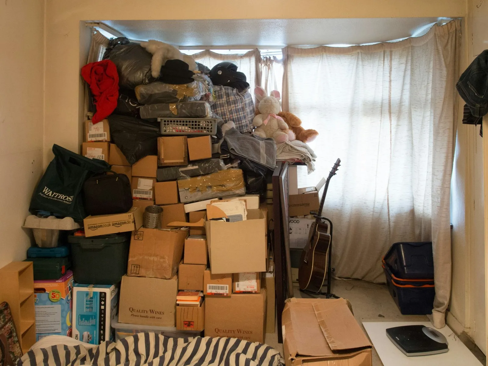 Mit Kartons und Möbeln vollgestelltes Zimmer vor der Entrümpelung