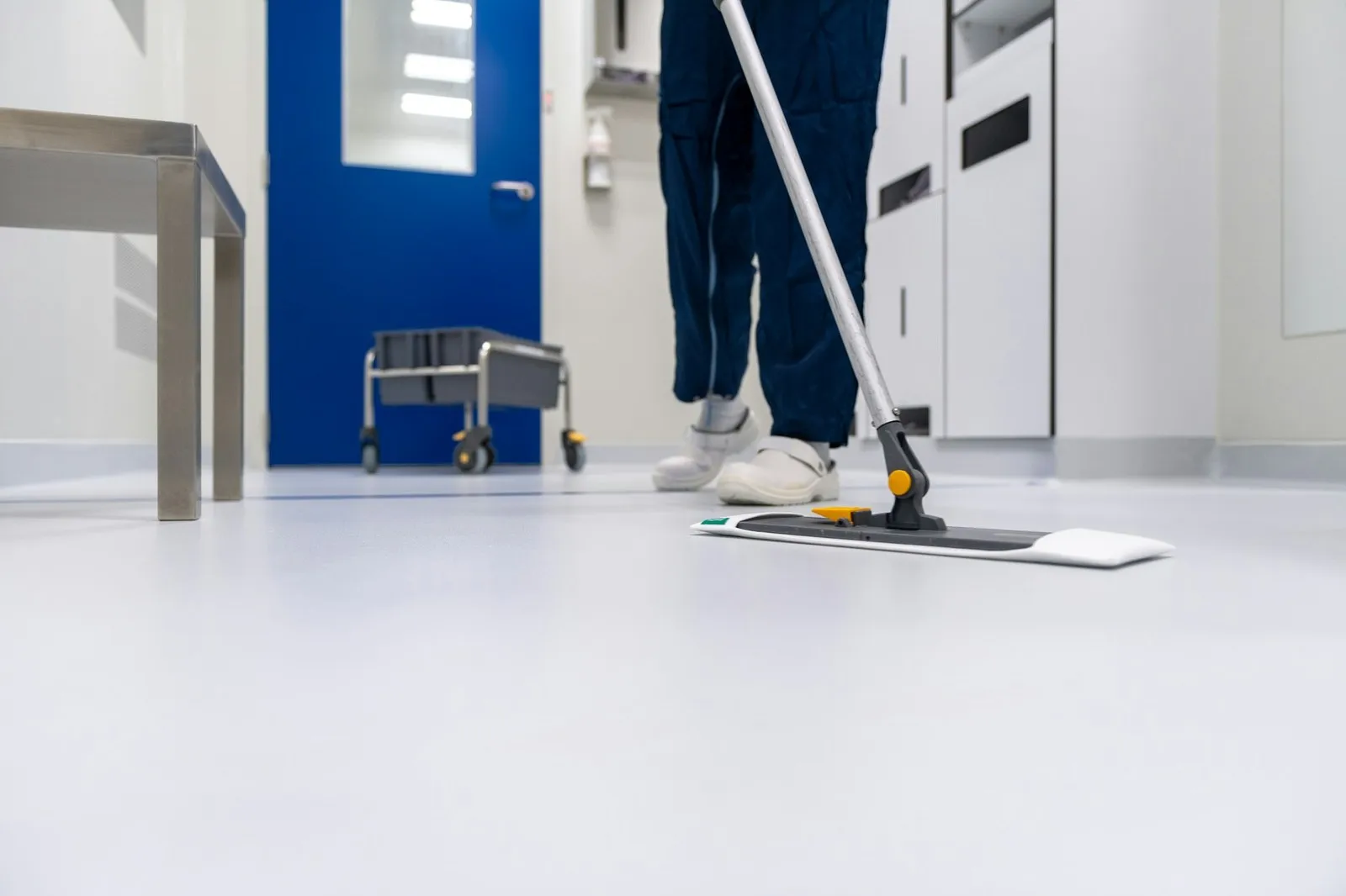 Reinigungskraft wischt einen hellen Flur mit dem Flachmopp