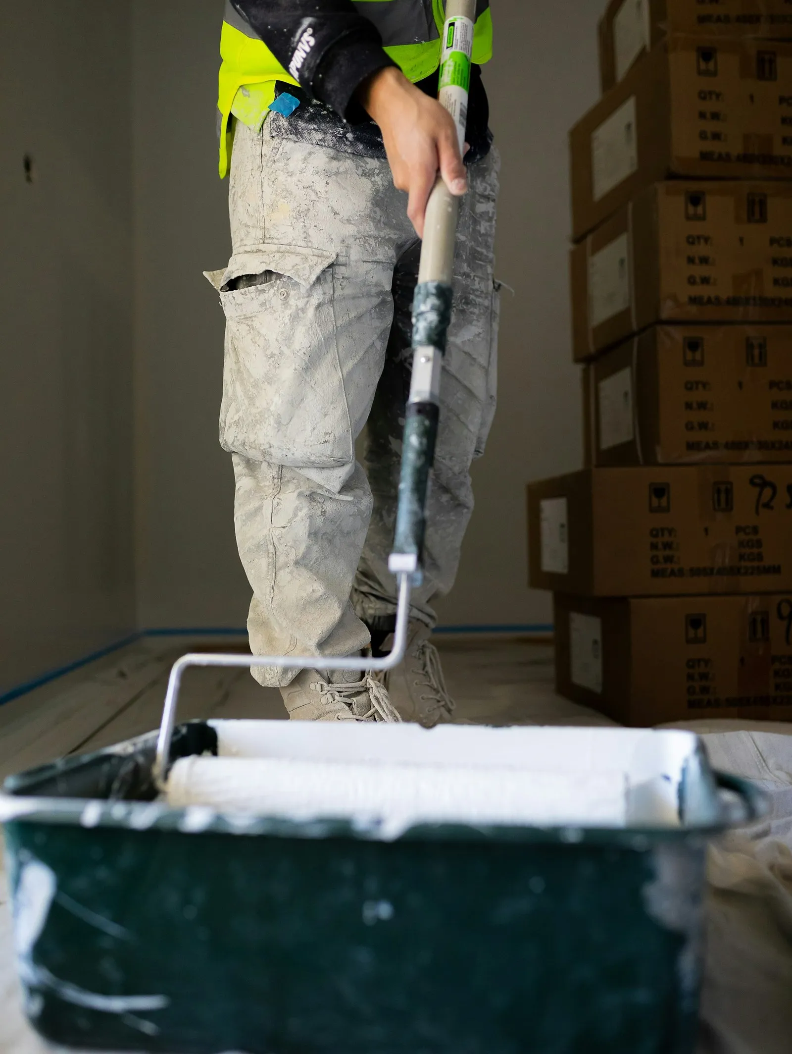Handwerker mit Farbrolle und Farbwanne in einem Raum