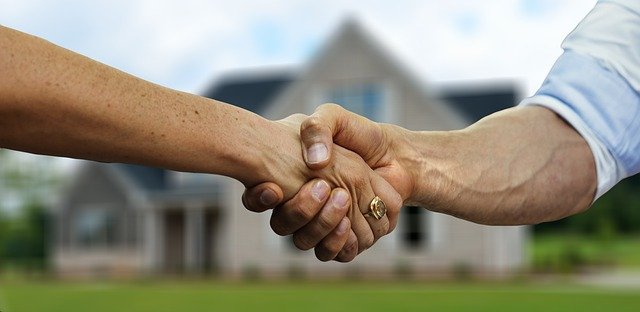 Zwei Hände zu einem Handschlag verbunden vor einem Haus mit Garten. So kann es aussehen, wenn unsere Stärken überzeugen und eine Zusammenarbeit entsteht.
